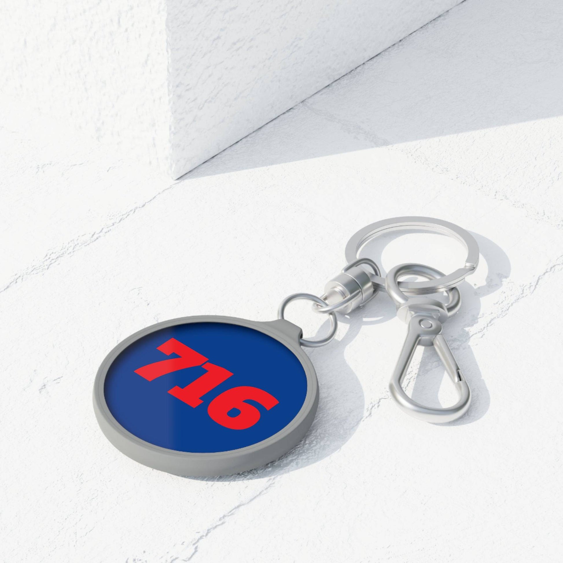 front of 716 blue metal keychain with red text on desk